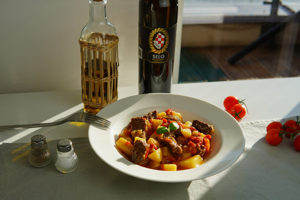 Hearty Shepherd's Stew with Beef (Čobanac od Junećeg Mesa) enriched with Croatian olive oil, served in a rustic bowl with a side of crusty bread, capturing the essence of traditional Croatian comfort food.